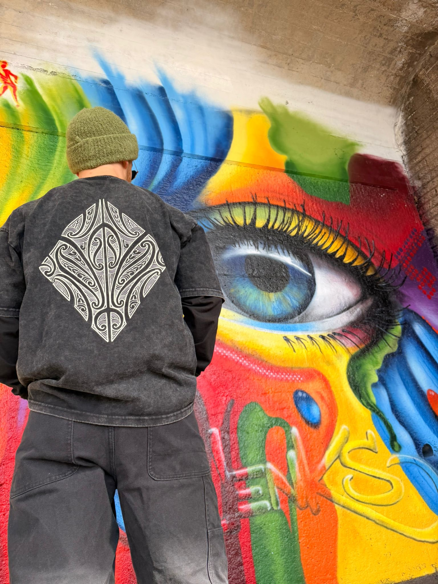 L.EGACY. Artist Series tee by Sykes worn in front of a graffiti mural